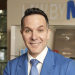 Professional man in a blue suit and tie smiling in an office setting.