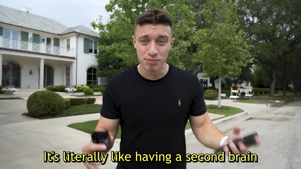 Man holding a black Plaud Note and phone. Text: It's literally like having a second brain.