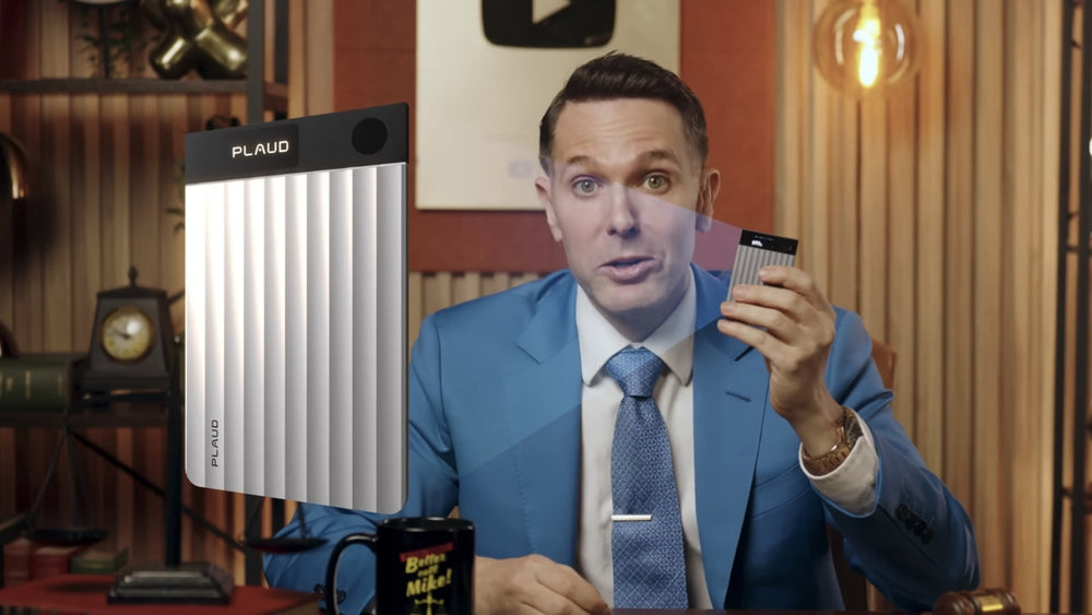 Man in a blue suit holding a silver Plaud Note Pro next to a large product overlay.