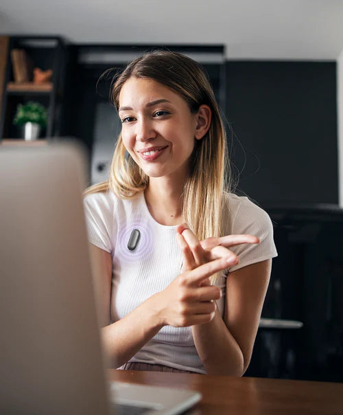 Woman wearing a Cosmic Gray Plaud NotePin on her shirt while gesturing during a video call on a laptop.