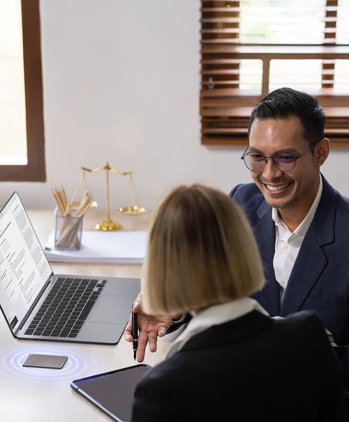 A black Plaud Note records a meeting between two professionals in an office setting.