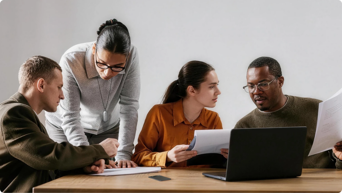 A woman wearing a silver Plaud NotePin on a lanyard collaborates with colleagues during a business meeting.