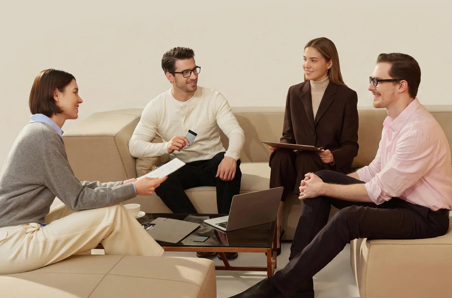 Four professionals sit on a beige couch in a meeting while a man holds a silver Plaud Note Pro AI voice recorder.