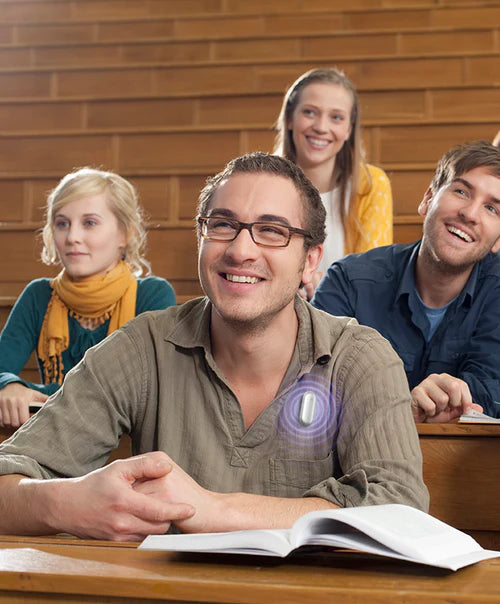 Student in a lecture hall wearing a silver Plaud NotePin on his shirt to record notes.