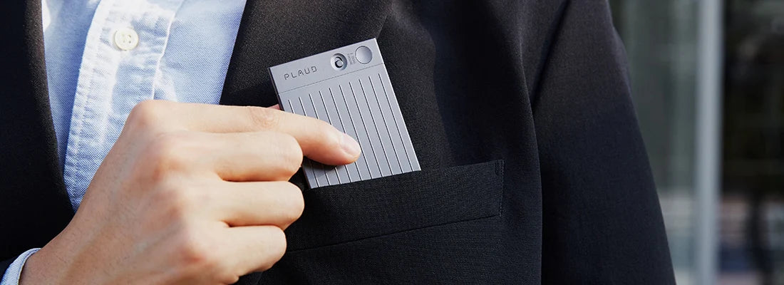 A person in a suit places a gray Plaud Note Pro into their blazer's chest pocket.
